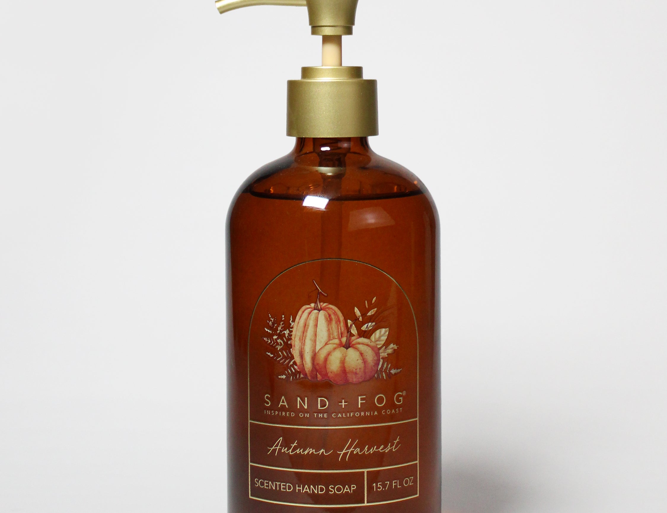 Amber liquid hand soap in a pump bottle, with an autumn harvest label and gold dispenser