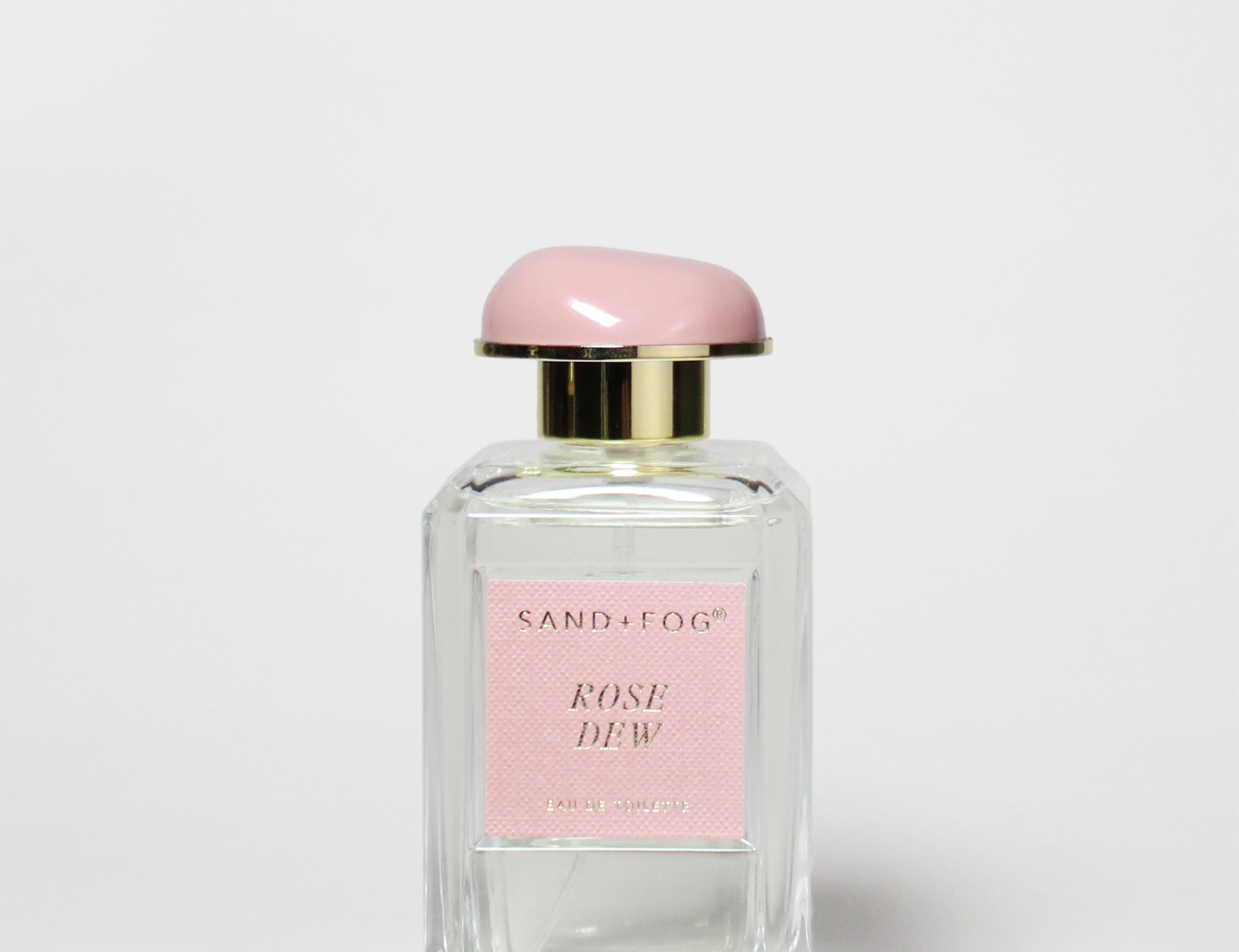 Clear glass eau de toilette bottle with pink cap and Rose Dew label