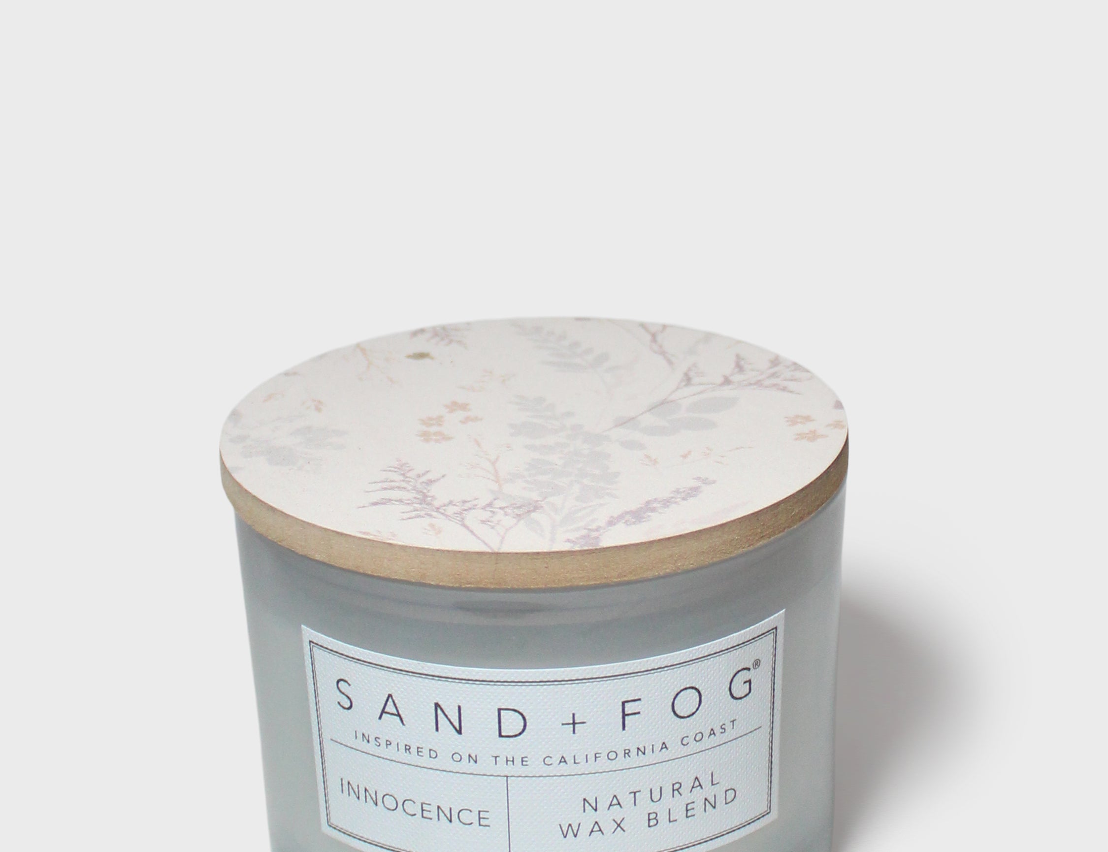 SAND + FOG scented candle in light blue glass jar with botanical lid and label