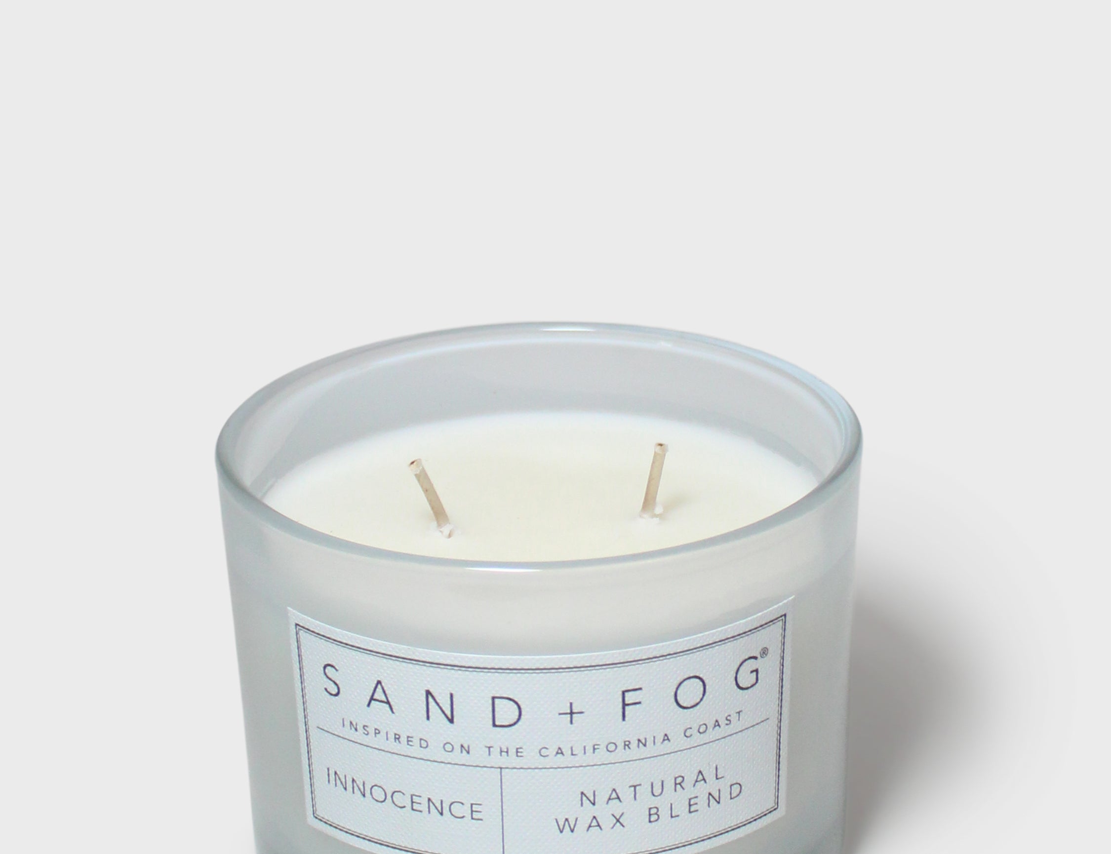 Scented candle in light blue glass jar with two wicks and front label