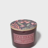 SAND + FOG scented candle in dark brown glass jar with floral lid and label