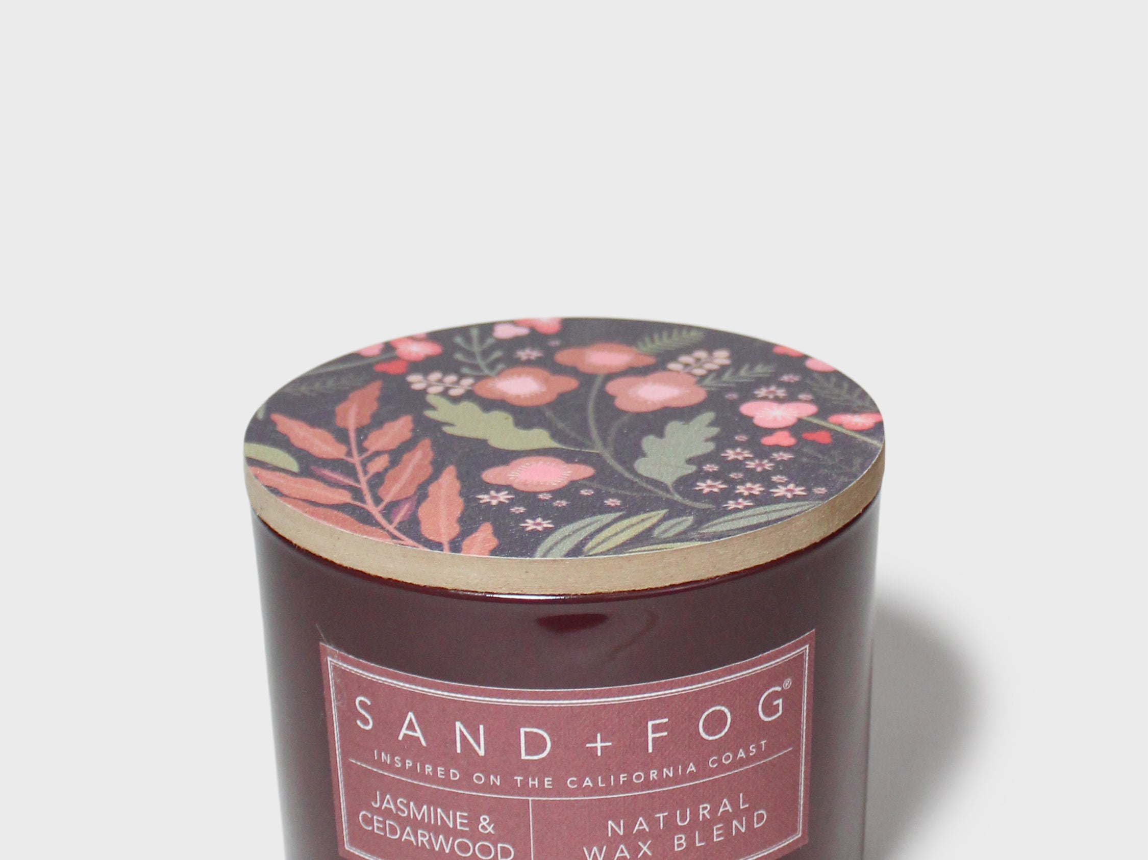 SAND + FOG scented candle in dark brown glass jar with floral lid and label
