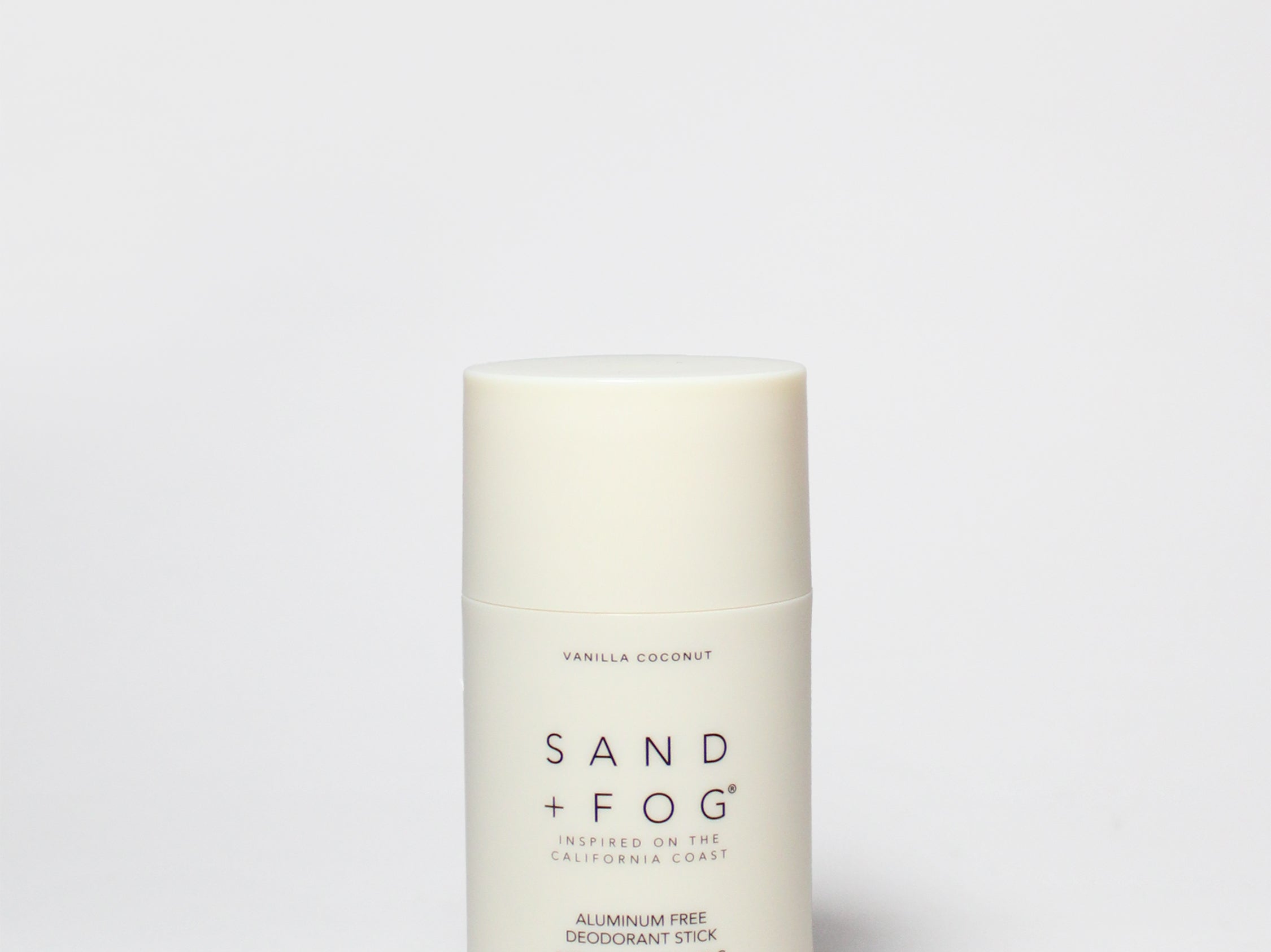 Vanilla coconut deodorant stick, off-white cylinder with Sand + Fog label