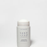 SAND + FOG deodorant stick, white container with open cap and violet sandalwood label