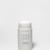 SAND + FOG deodorant stick, white container with open cap and violet sandalwood label
