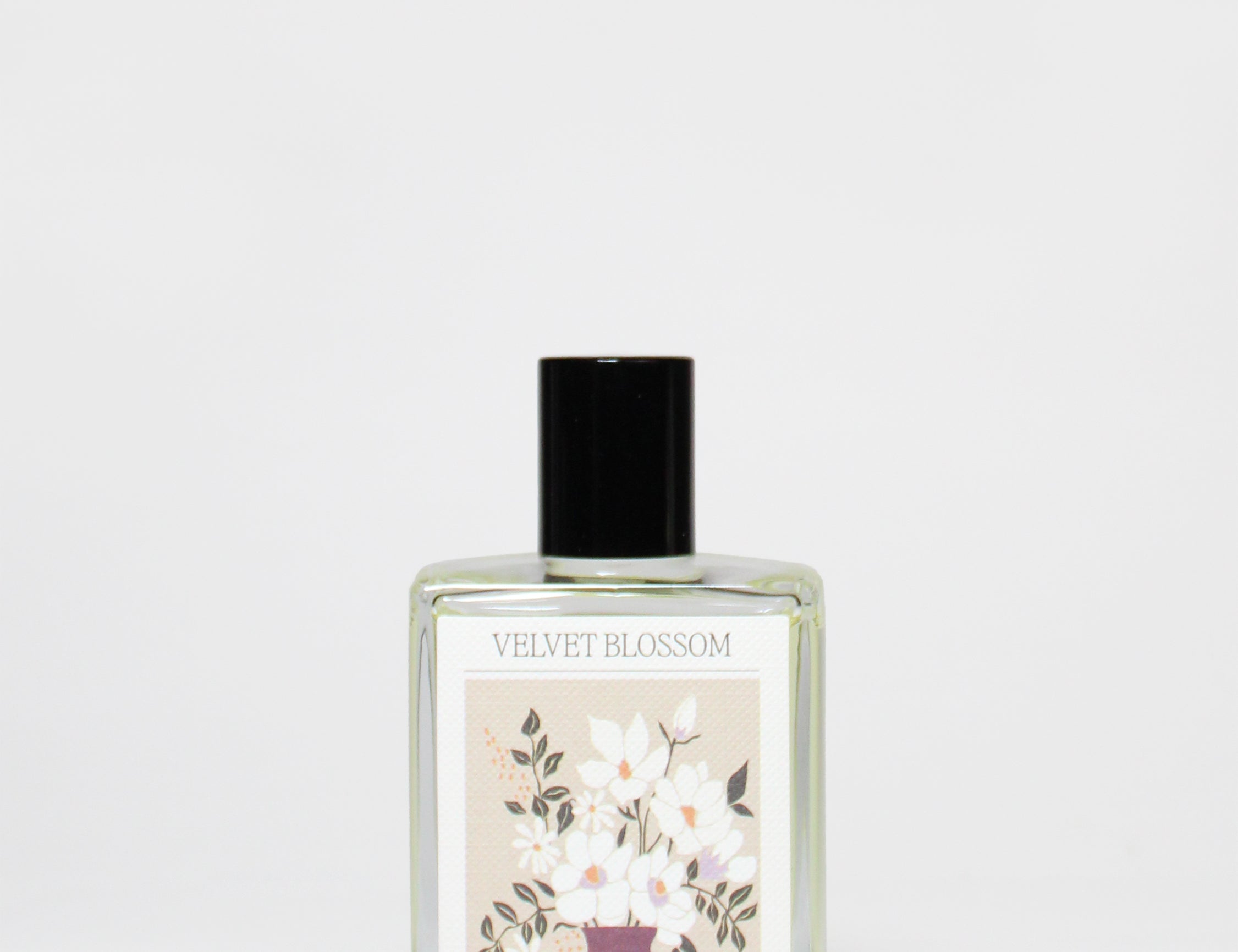 Perfume oil bottle with clear glass, black cap, and floral label