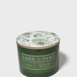 Green glass jar scented candle with floral lid design and Sand + Paws Forest label