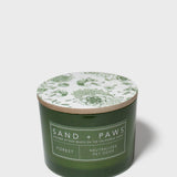 Green glass jar scented candle with floral lid design and Sand + Paws Forest label