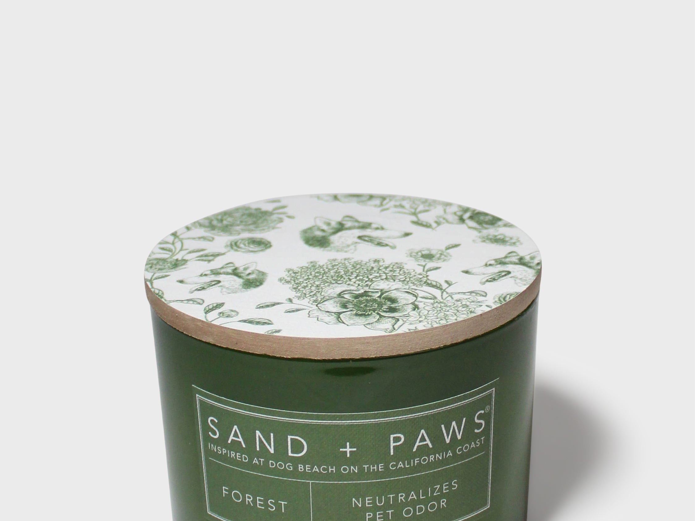 Green glass jar scented candle with floral lid design and Sand + Paws Forest label