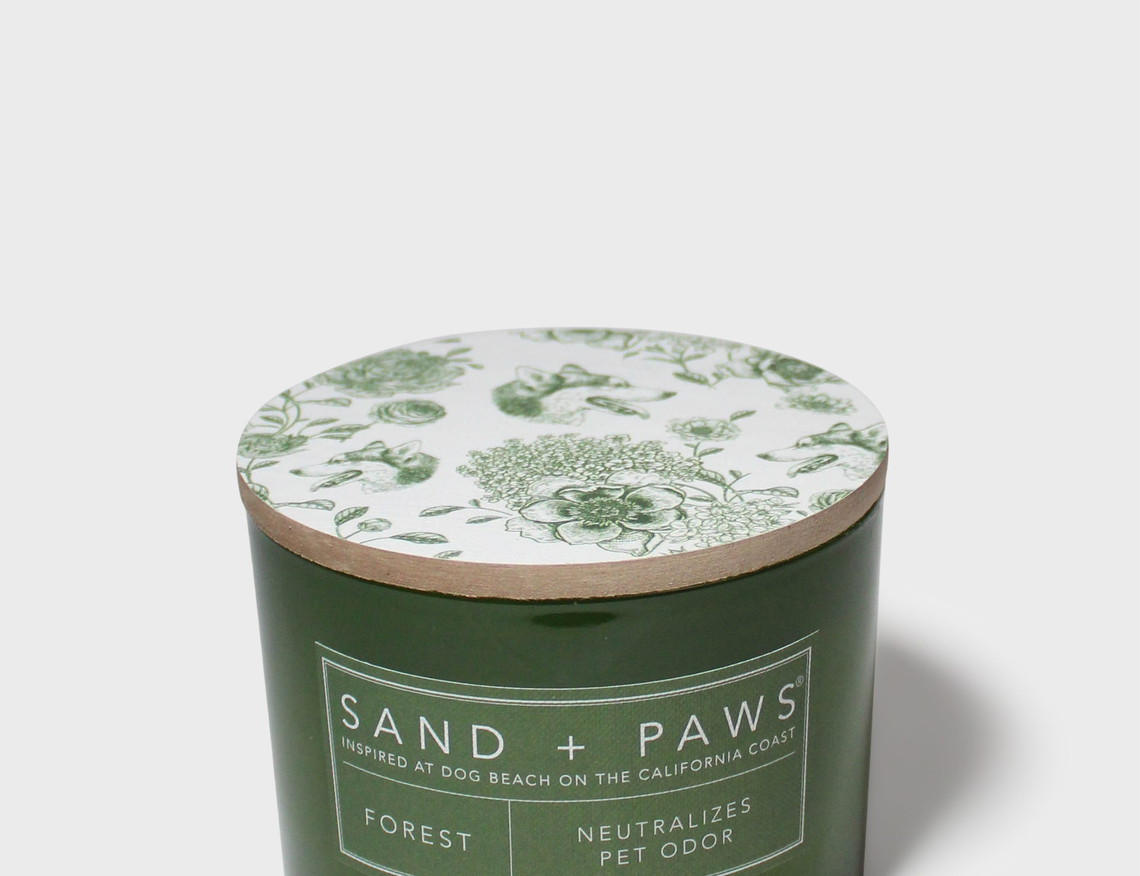 Green glass jar scented candle with floral lid design and Sand + Paws Forest label