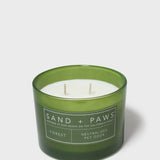 Green glass jar scented candle with white wax and Sand + Paws Forest label
