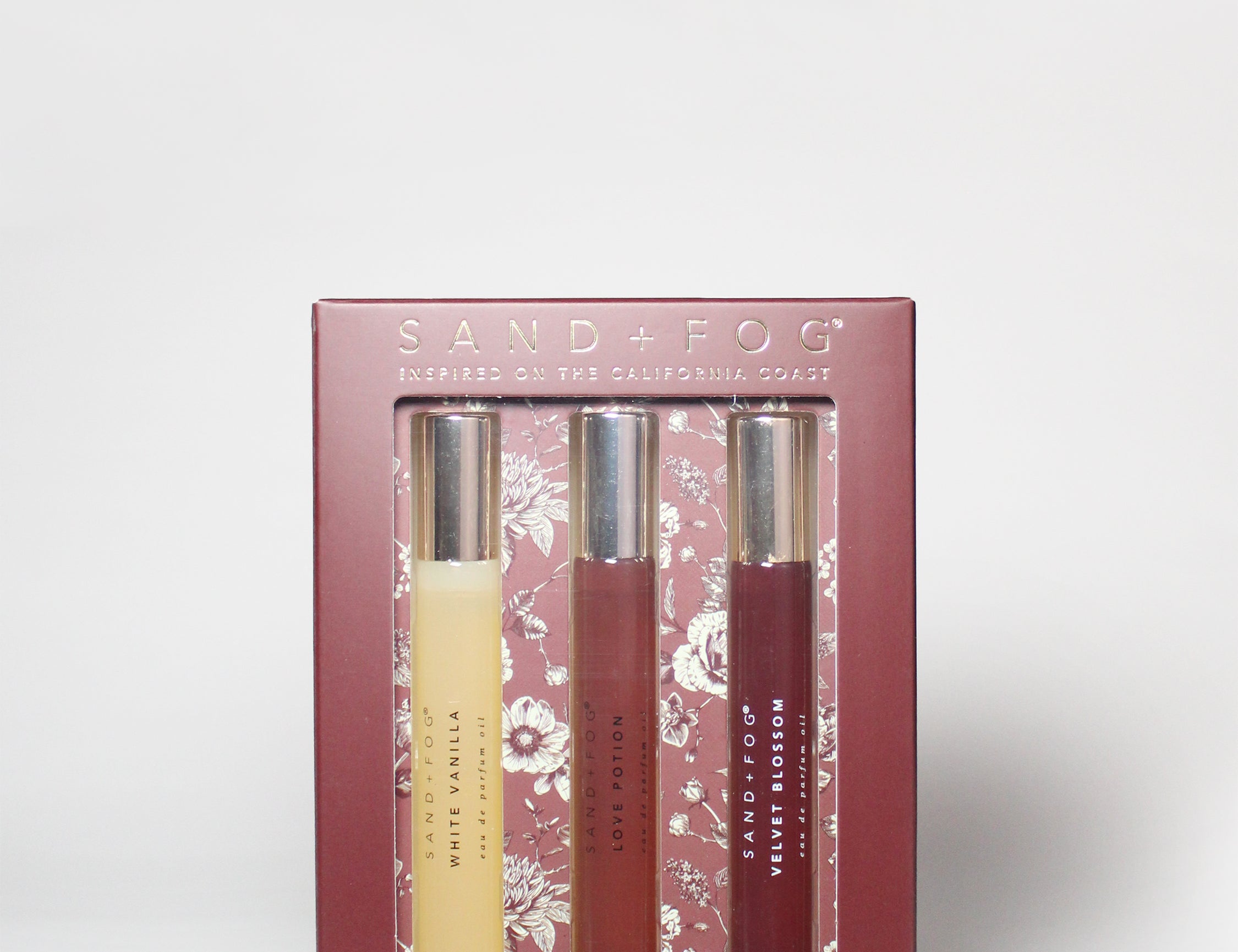 Perfume oil rollerball set in a pink box, four dark and gold roller bottles