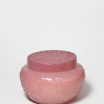 Pink embossed glass candle jar with its matching lid on top.
