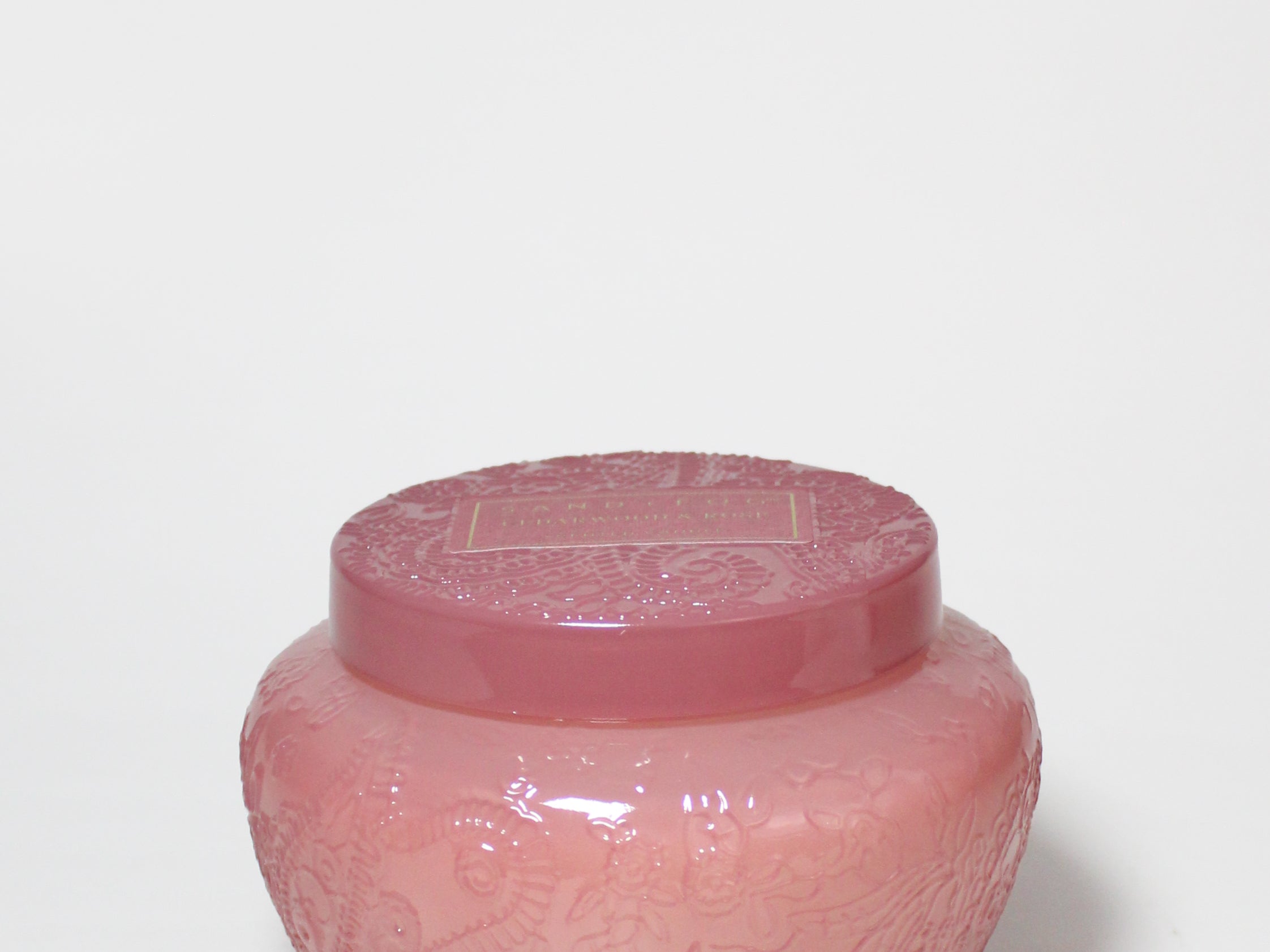 Pink embossed glass candle jar with its matching lid on top.