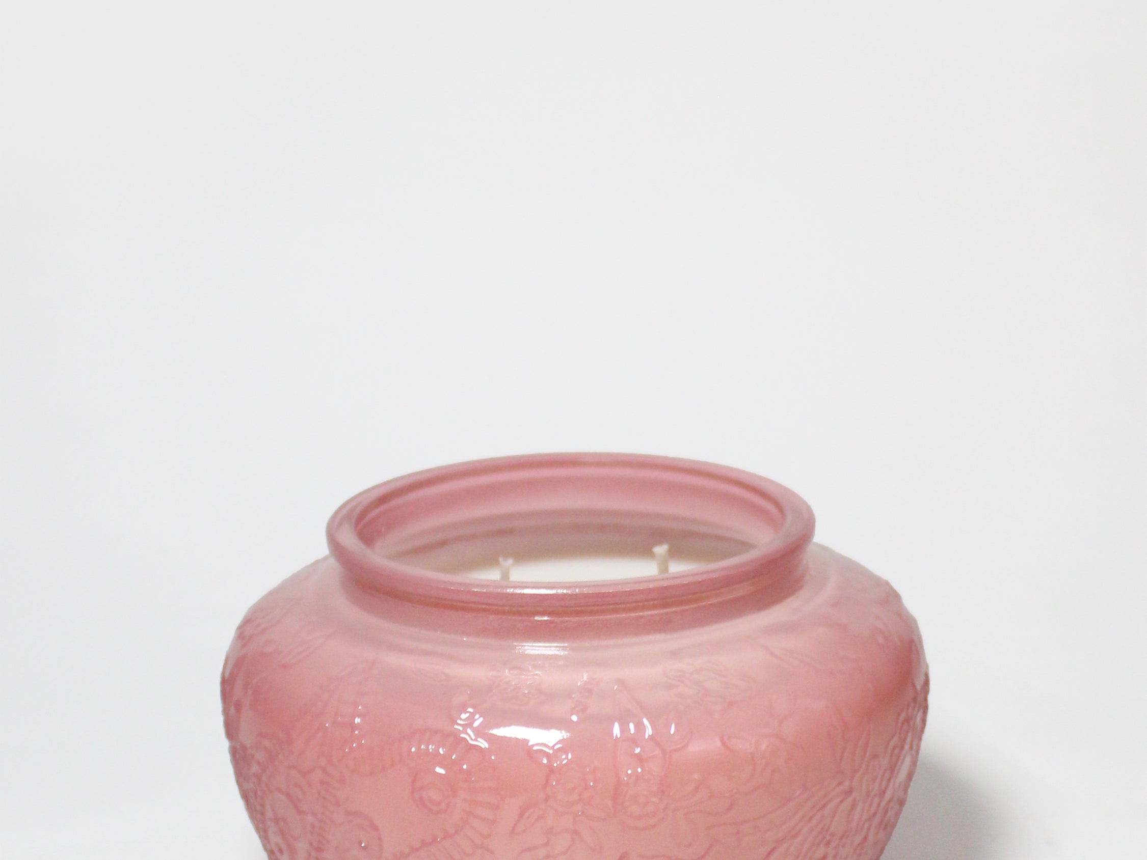 Cedarwood and rose scented candle in a pink embossed glass jar with two wicks.