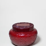 17 oz scented candle in a red embossed glass jar with a matching lid