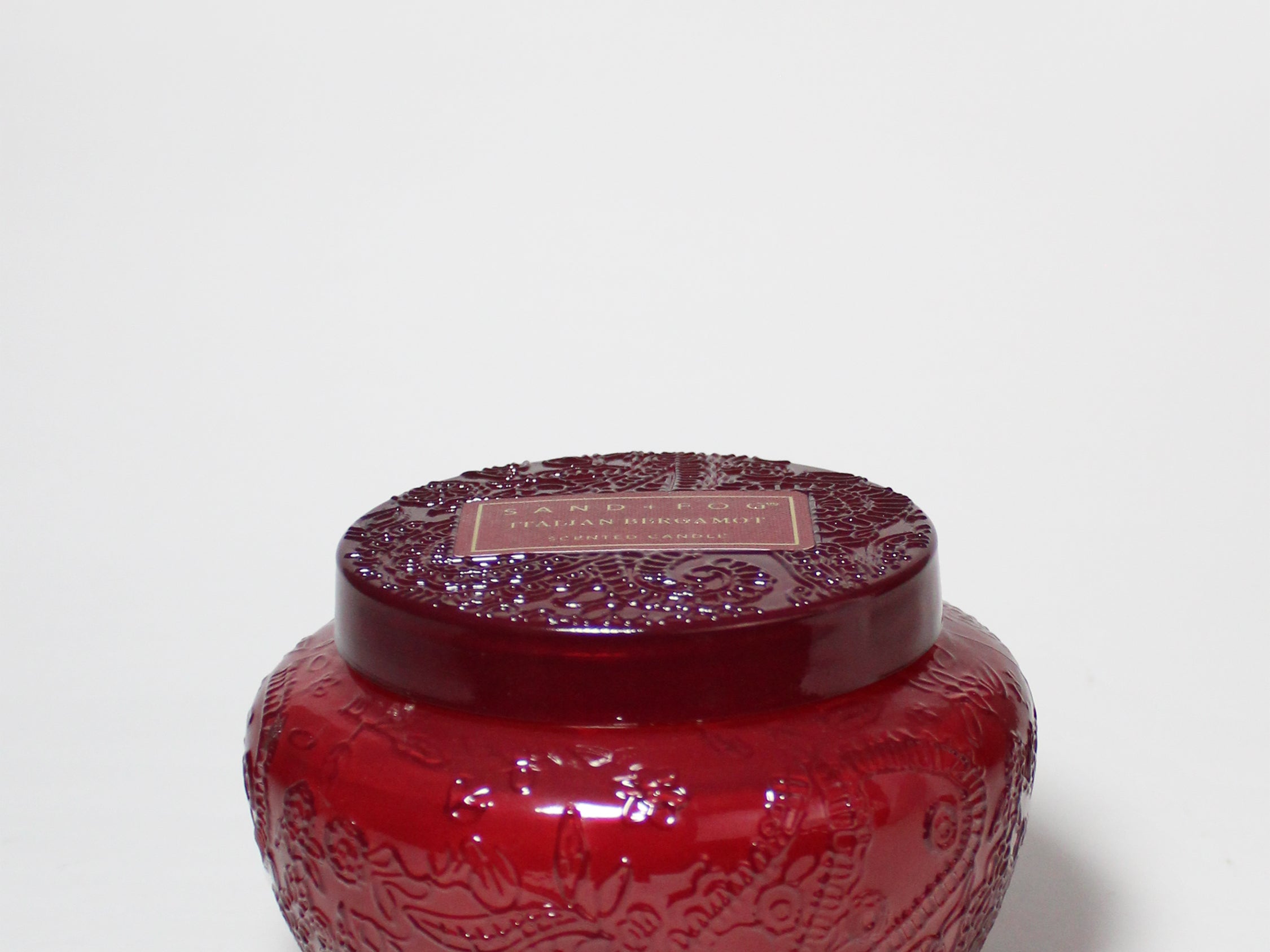17 oz scented candle in a red embossed glass jar with a matching lid