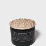 Black jar scented candle with beige patterned lid and Sand+Fog label