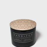 Black jar scented candle with beige patterned lid and Sand+Fog label