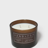 Scented candle in dark brown glass jar with two wicks and Sand+Fog label
