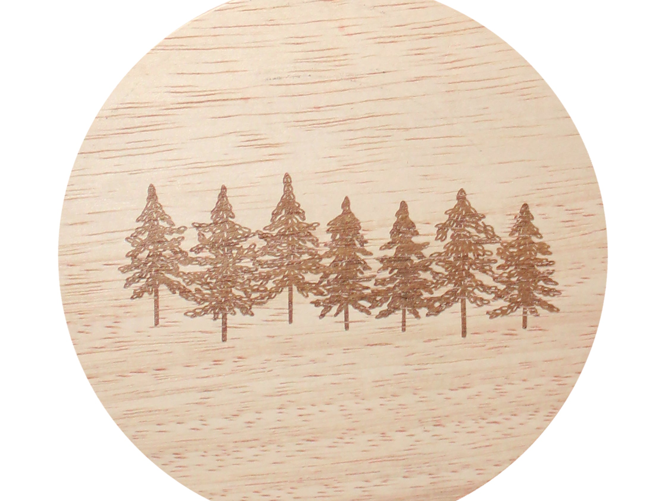 Round candle label with pine tree scene on light wood-grain background