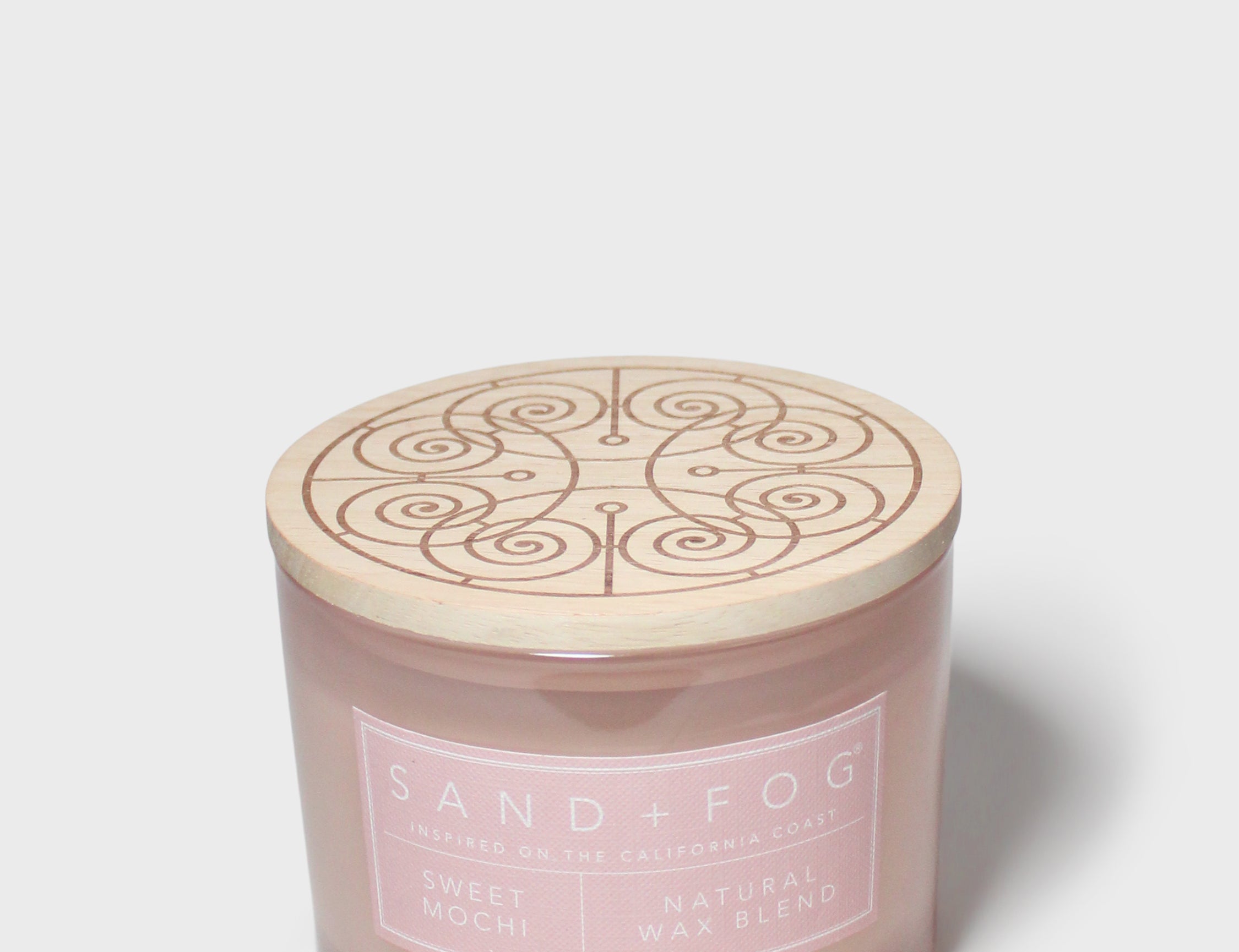 Top view of pink Sand + Fog scented candle jar with embossed swirl lid
