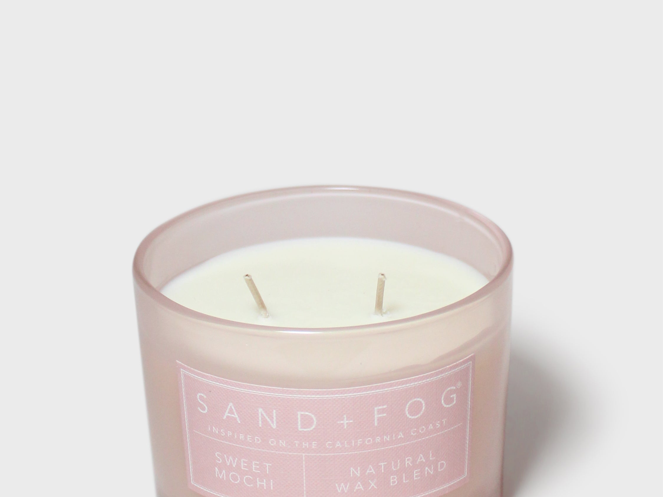 Pink glass jar scented candle with white wax and Sand + Fog label
