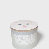Crisp white scented candle with Sand + Paws label and cat face lid graphic