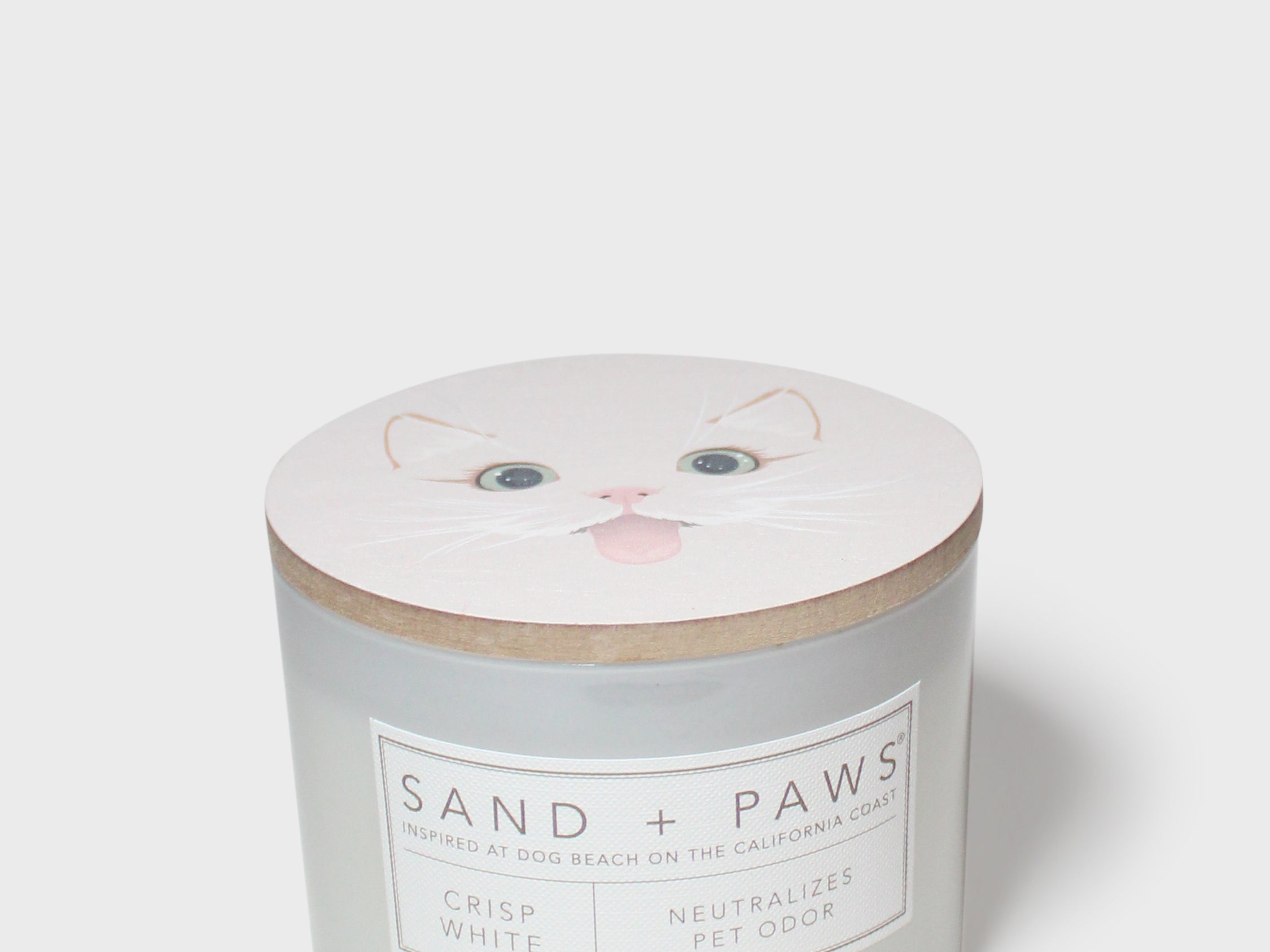 Crisp white scented candle with Sand + Paws label and cat face lid graphic