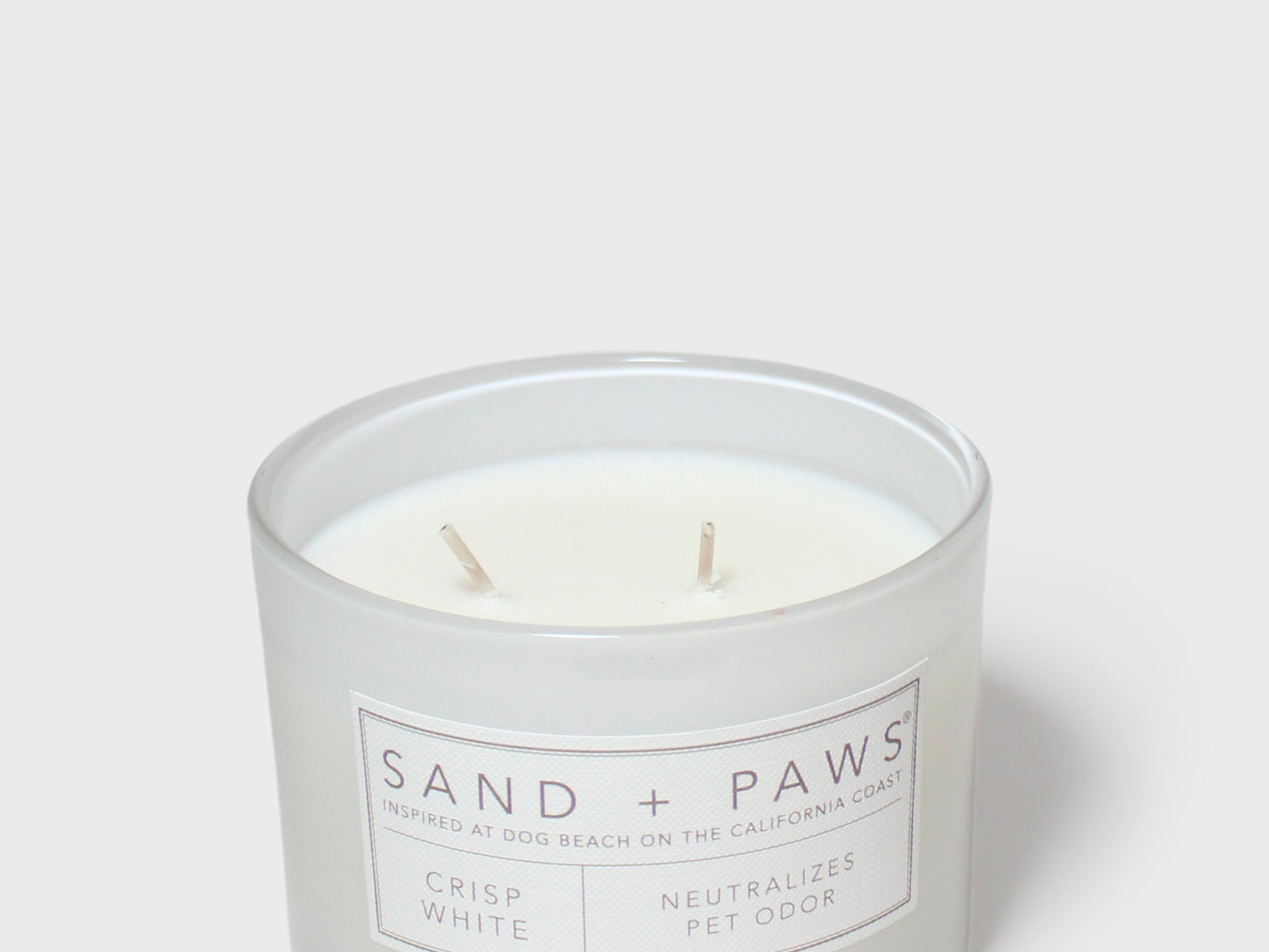 Crisp white scented candle in frosted jar with two wicks and Sand + Paws label