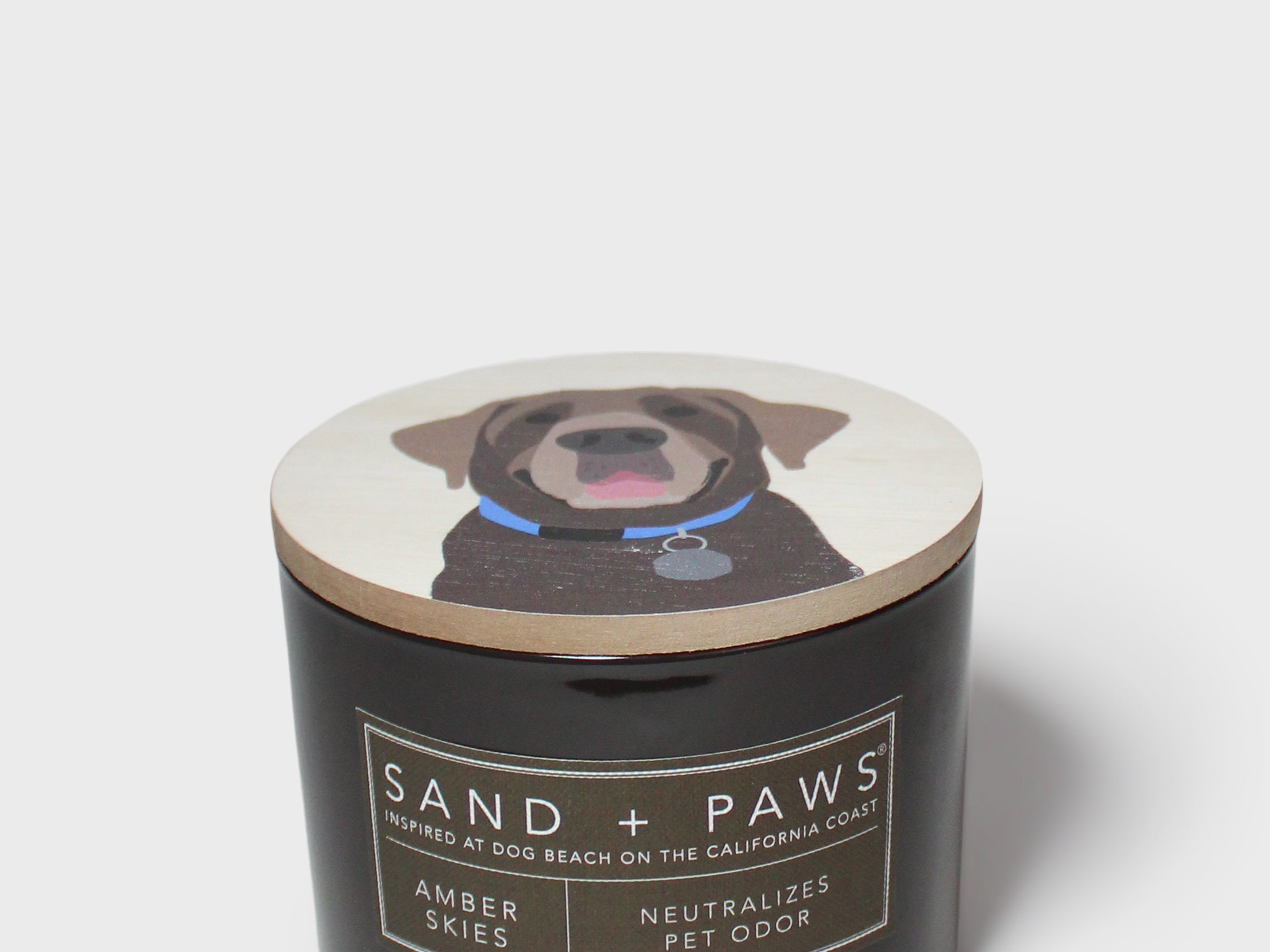 Sand + Paws scented candle in black jar with dog graphic lid and label