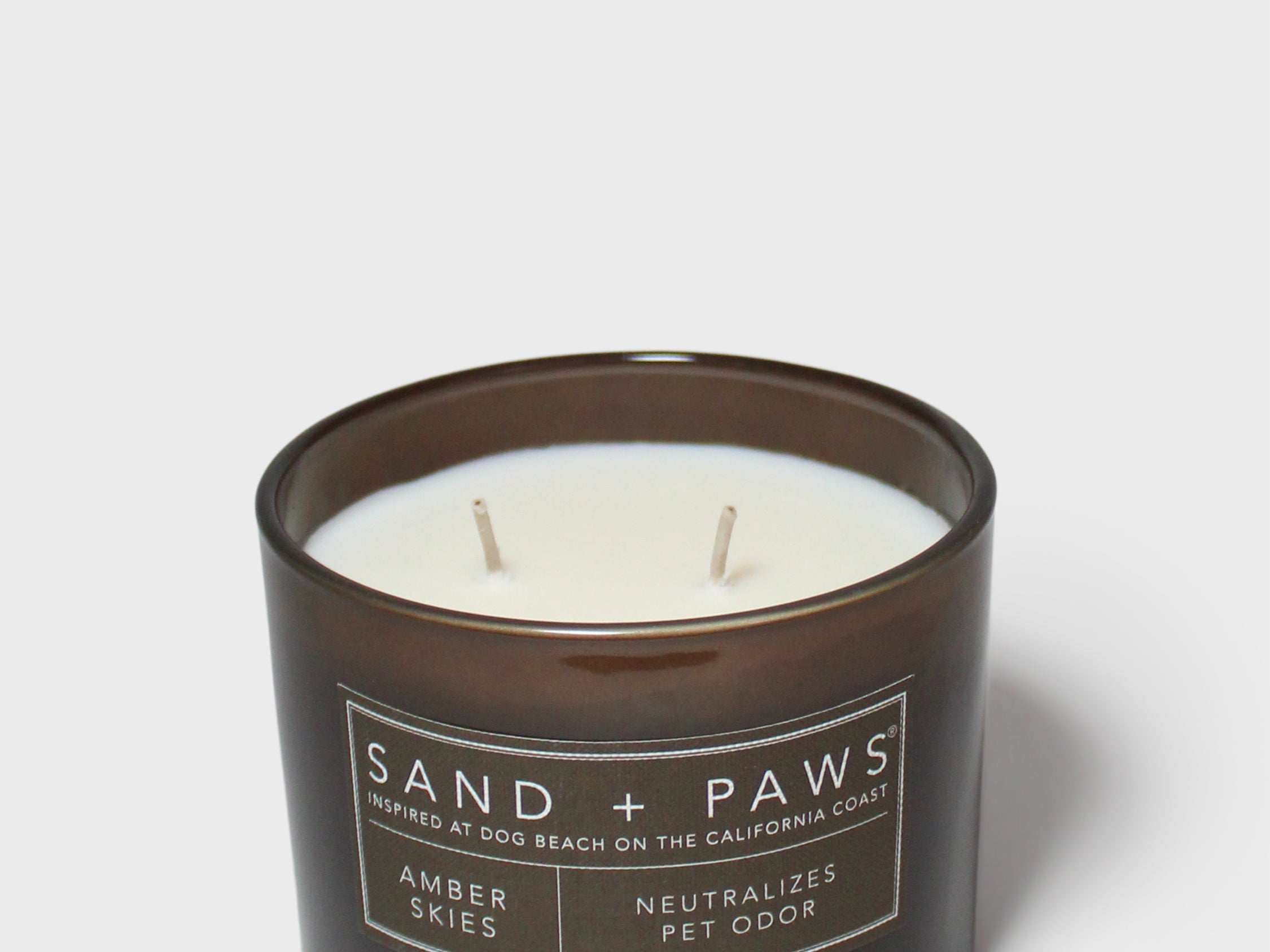 12 oz scented candle in dark glass jar with white wax and two wicks, amber skies label