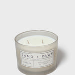 Scented candle in clear glass jar with Sand + Paws label