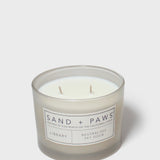 Scented candle in clear glass jar with Sand + Paws label