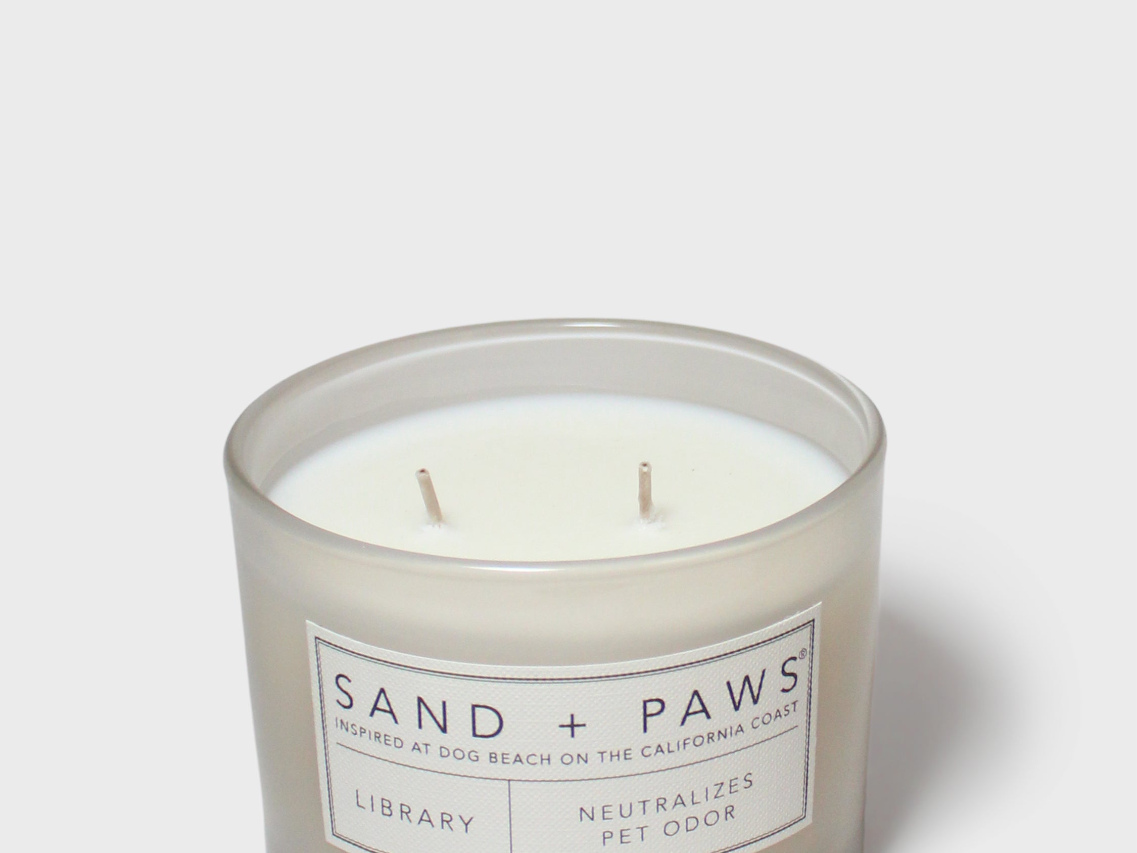 Scented candle in clear glass jar with Sand + Paws label