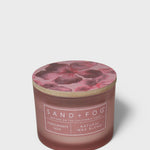 Scented candle in brown glass jar with pink pomegranate label and foil lid