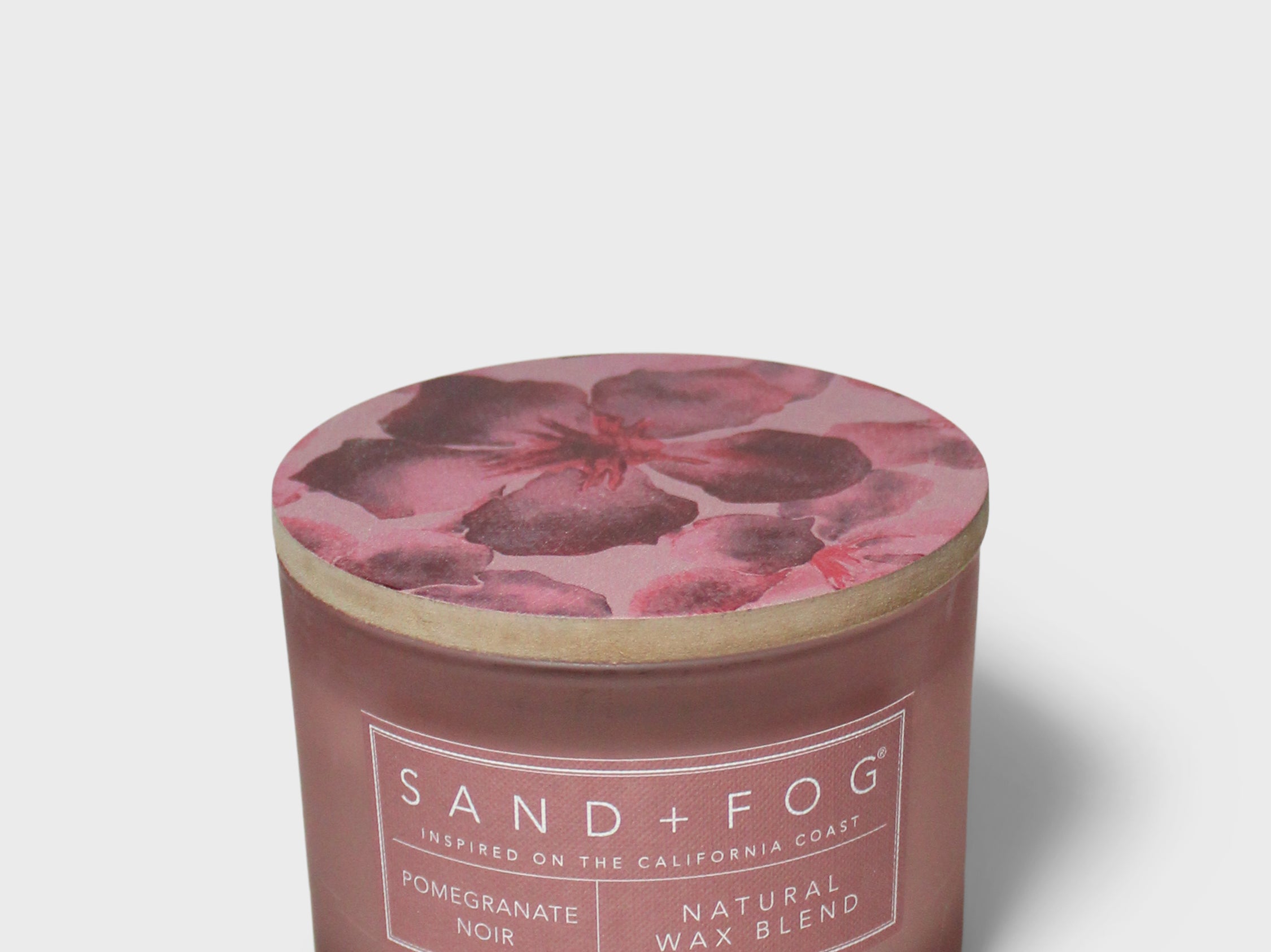 Scented candle in brown glass jar with pink pomegranate label and foil lid