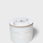 Scented candle jar with dog portrait lid and 'Sand + Paws' label on front