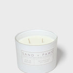 Scented candle jar with 'Sand + Paws' label, two wooden wicks visible