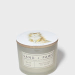 White linen scented candle in frosted glass jar with Sand + Paws label