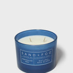 12 oz scented candle in blue glass jar with white wax and SAND+FOG label