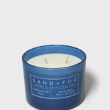 12 oz scented candle in blue glass jar with white wax and SAND+FOG label