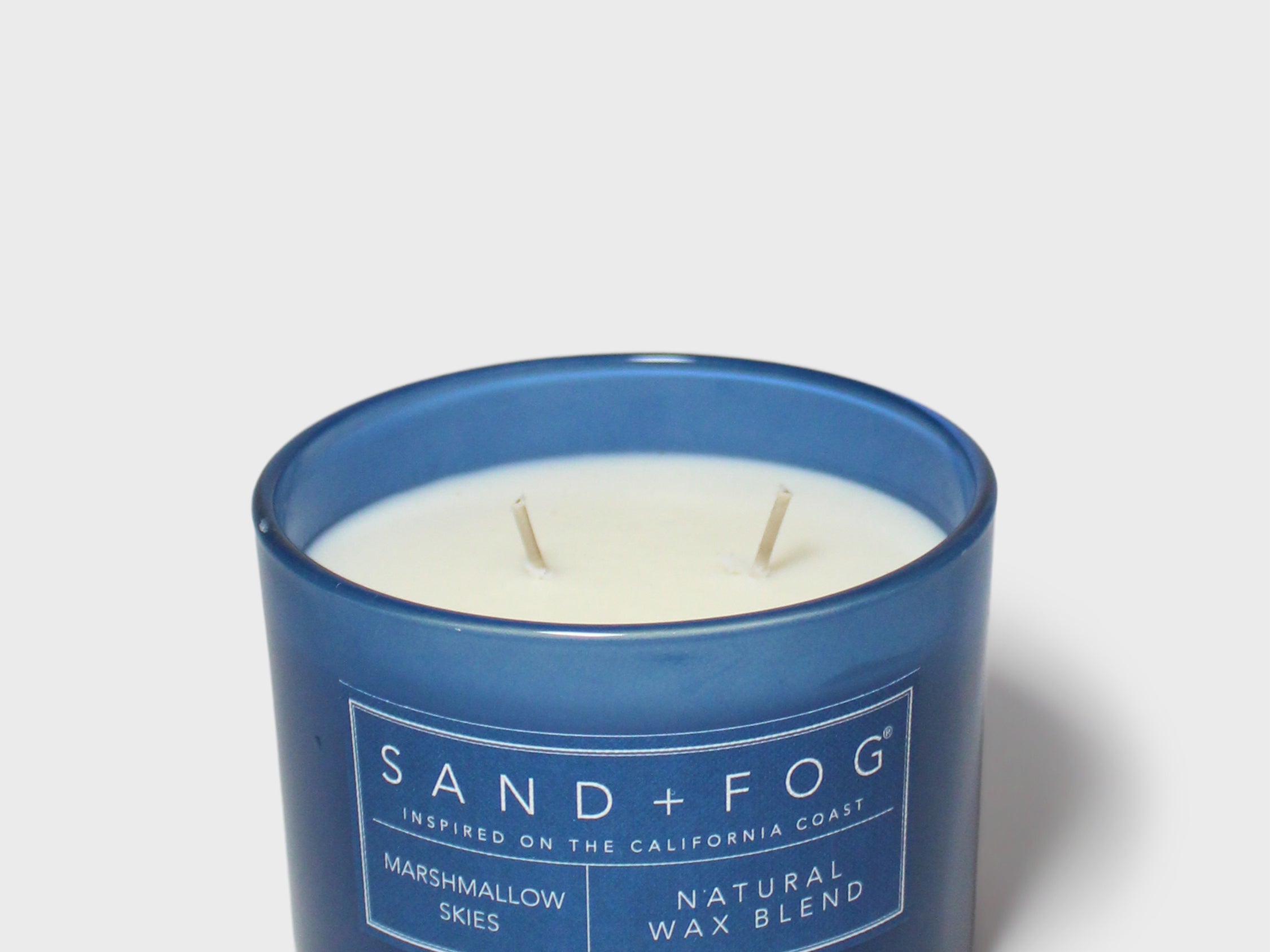 12 oz scented candle in blue glass jar with white wax and SAND+FOG label