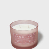 Scented candle in brown glass jar with white wax and Sand+Fog label