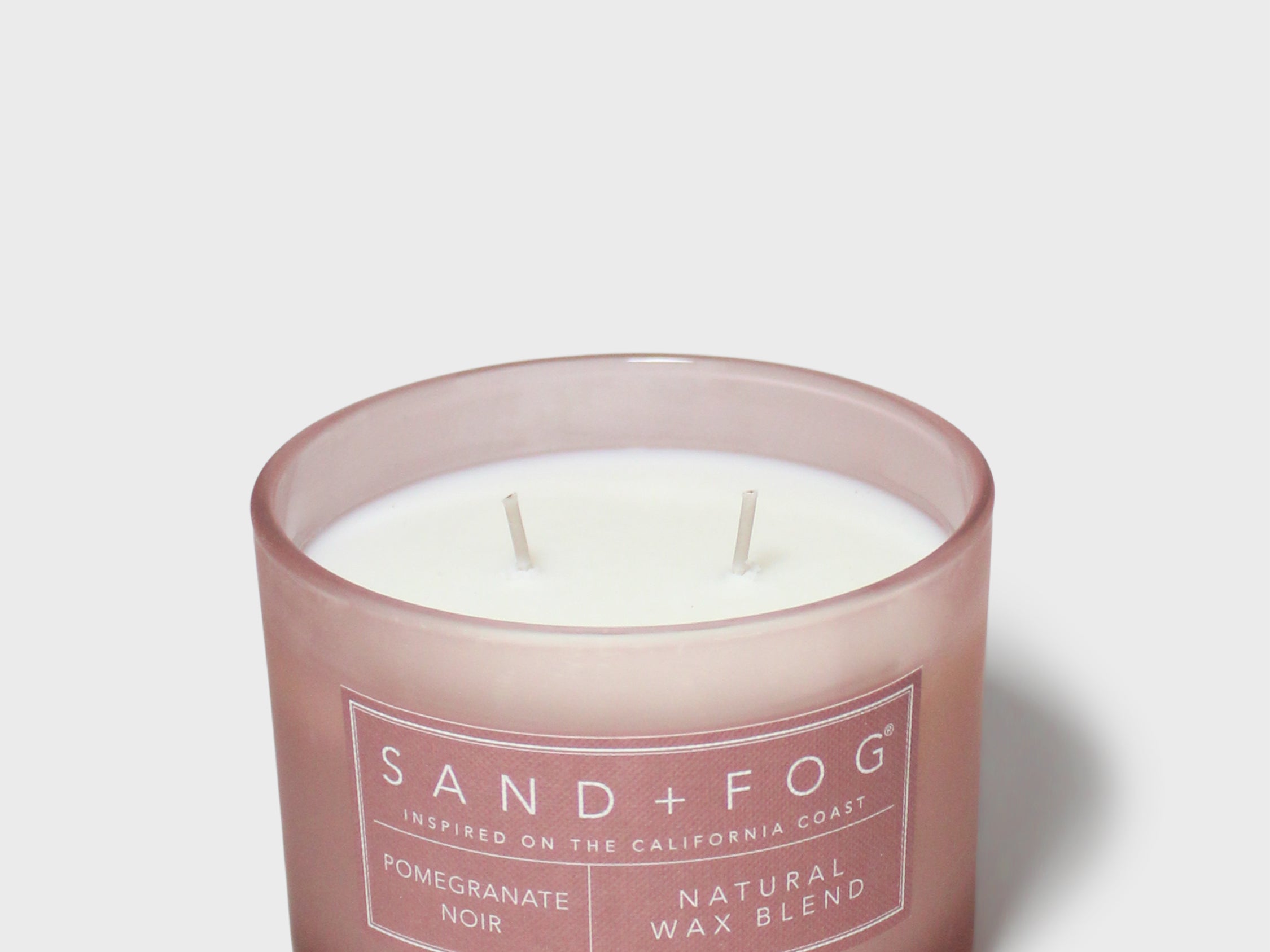 Scented candle in brown glass jar with white wax and Sand+Fog label