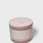 Scented candle in dark brown jar with pink floral-pattern lid and white label