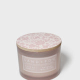Scented candle in dark brown jar with pink floral-pattern lid and white label