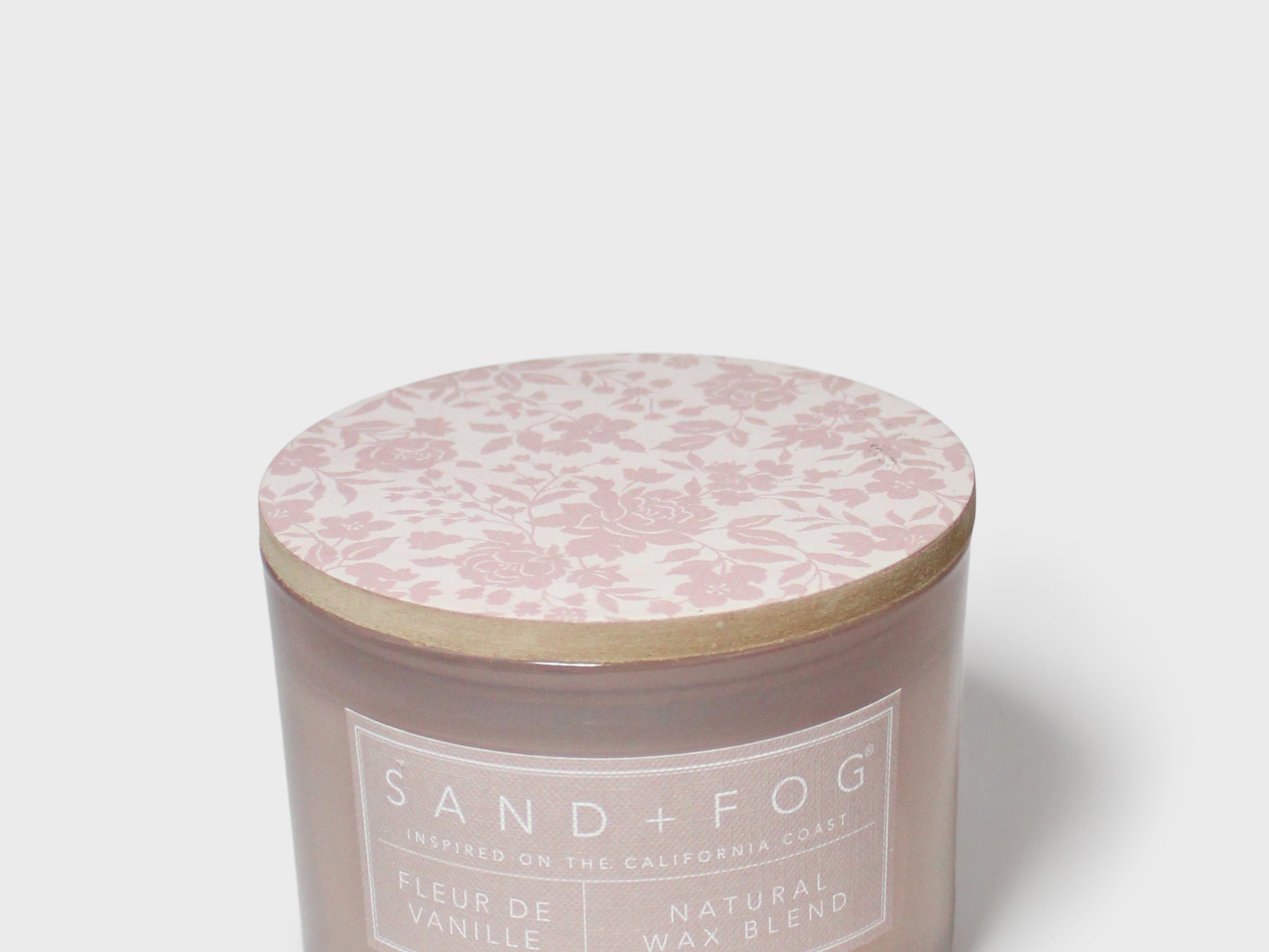 Scented candle in dark brown jar with pink floral-pattern lid and white label