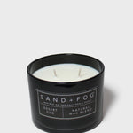 Black glass scented candle with Sand+Fog label, white wax and two wicks