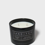 Black glass scented candle with Sand+Fog label, white wax and two wicks